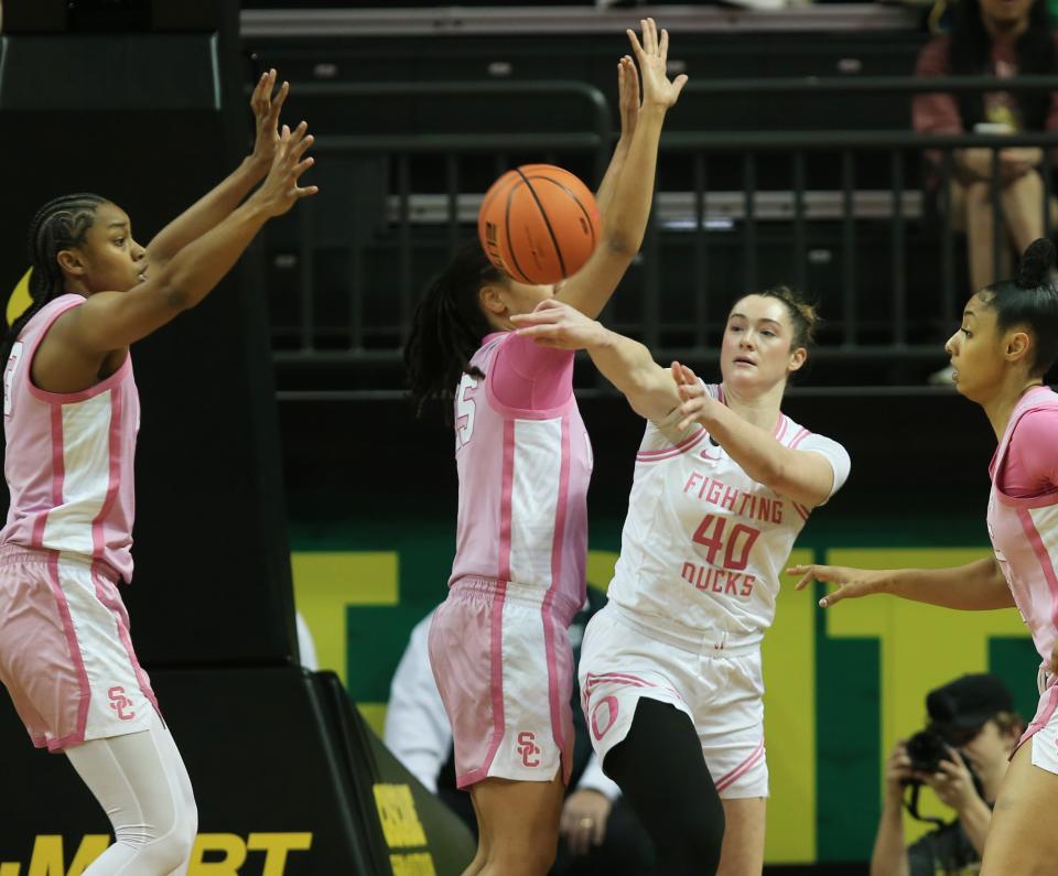 Oregon’s Grace VanSlooten, center, passes the ball out under pressure from USC players during the first half at Matthew Knight Arena in Eugene Friday, Feb. 16, 2024.