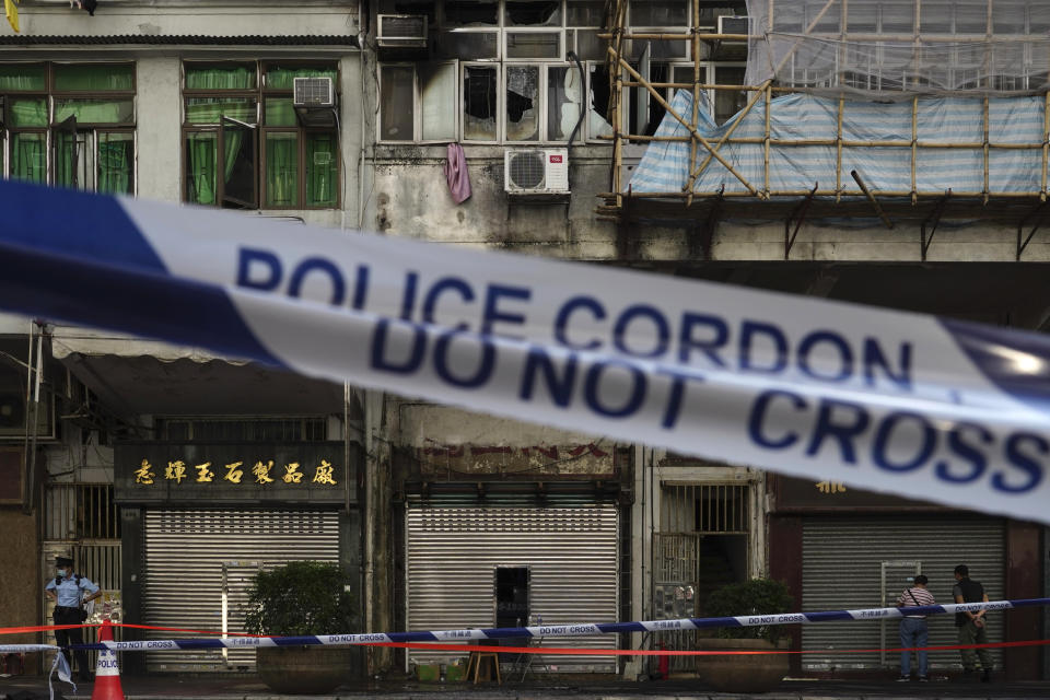 A police cordon line is set at a fire site, top center with broken windows, in Hong Kong Monday, Nov. 16, 2020. City authorities said a fire in a crowded residential district in Hong Kong has "caused a number of deaths and injuries". (AP Photo/Vincent Yu)