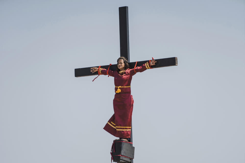 Mary Jane Sazon, the only woman to join in the crucifixion in the village this year, remains calm while she is nailed on a wooden cross as part of Good Friday rituals in the village of San Pedro Cutud, Pampanga province, northern Philippines, Friday, April 19, 2019. Sazon has joined the crucifixion ritual for more than a dozen times, according to tourism officials. She says this year's devotion is dedicated to her sickly mother. Over a thousand Filipino Roman Catholic devotees and tourists flocked to a farming village north of Manila on Friday to witness the crucifixion of several devotees in a costumed reenactment of Jesus Christ's sufferings, a gory annual tradition church leaders frown upon. (AP Photo/Iya Forbes)