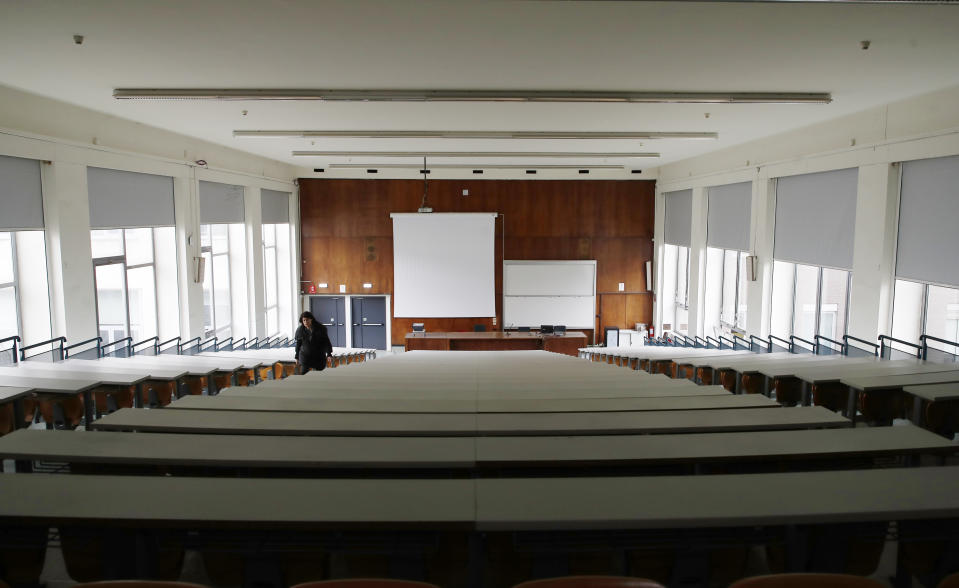A woman walks in an empty classroom at the Statale University, in Milan, Italy, Thursday, March 5, 2020. Italy's virus outbreak has been concentrated in the northern region of Lombardy, but fears over how the virus is spreading inside and outside the country has prompted the government to close all schools and Universities nationwide for two weeks. (AP Photo/Antonio Calanni)