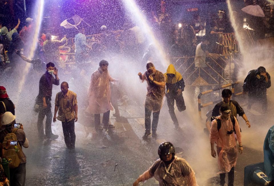 Pro democracy demonstrators face water canons as police try to clear the protest venue in Bangkok, Thailand, Friday, Oct. 16, 2020. Thailand prime minister has rejected calls for his resignation as his government steps up efforts to stop student-led protesters from rallying in the capital for a second day in defiance of a strict state of emergency. (AP Photo/Gemunu Amarasinghe)