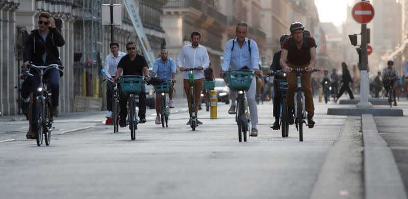 FILE PHOTO: People ride bicycles in the Rue de Rivoli in a warm and sunny day in Paris