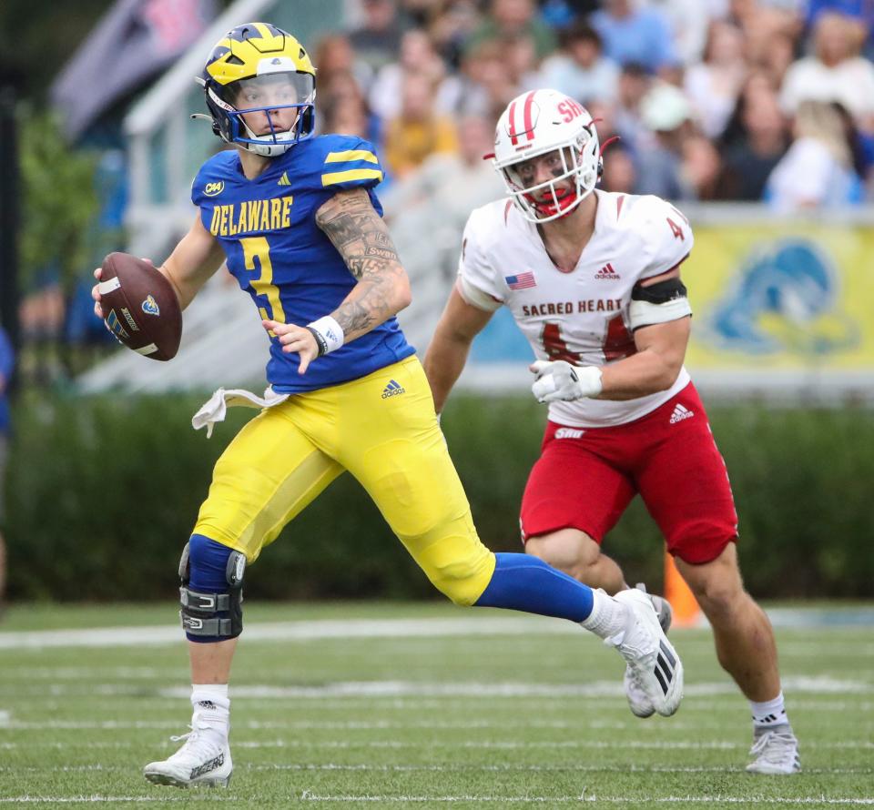 Delaware quarterback Zach Marker looks for a receiver as he's chased by Sacred Heart's Peter Schanne in the second quarter at Delaware Stadium, Saturday, Sept. 28, 2024.