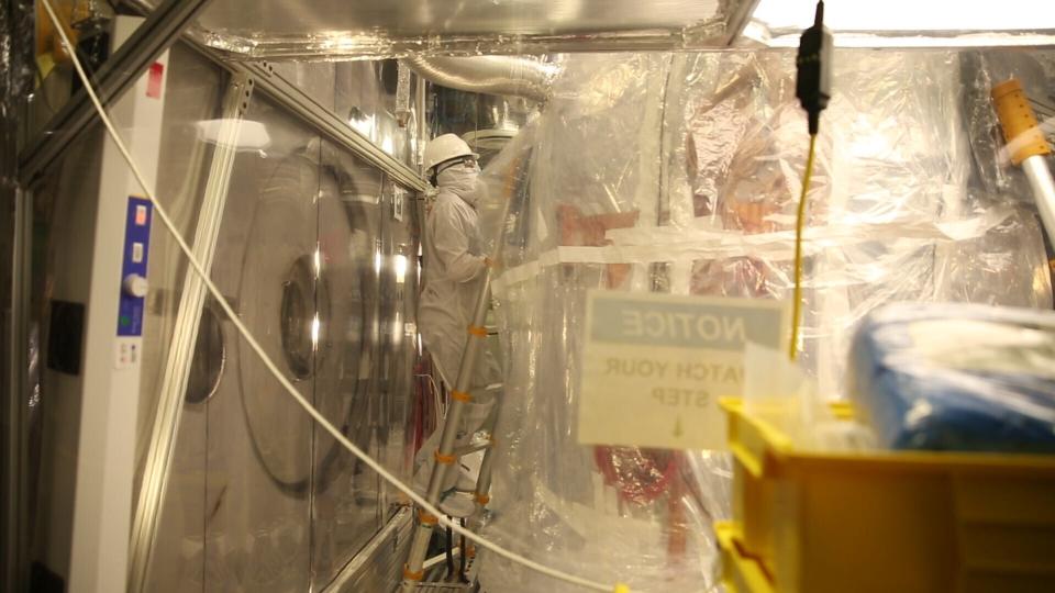 A lab worker wearing a full-body suit to avoid contaminating the dark matter detector works in the Sanford Underground Research Facility in Lead, S.D., on Dec. 8, 2019. Scientists have begun a new search for mysterious dark matter in a former gold mine a mile underground. Dark matter makes up the vast majority of the mass of the universe but scientists don't know what it is. (AP Photo/Stephen Groves)