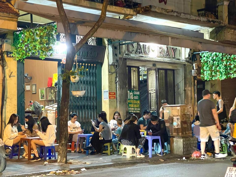 People sitting on stools in Hanoi eating street food.