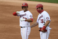 Washington Nationals' Juan Soto, left, reacts at first after his single during the second inning of a baseball game against the New York Mets, Sunday, Sept. 27, 2020, in Washington. Nationals first base coach Bob Henley, right, looks on. (AP Photo/Nick Wass)