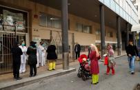 People stand in a queue to enter into a Medical Center, as medical staff check them, during an outbreak of coronavirus disease (COVID-19) in Barcelona