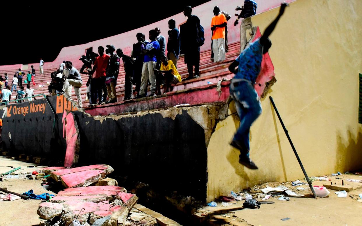 People look at the scene after a wall collapsed at Demba Diop  - AFP