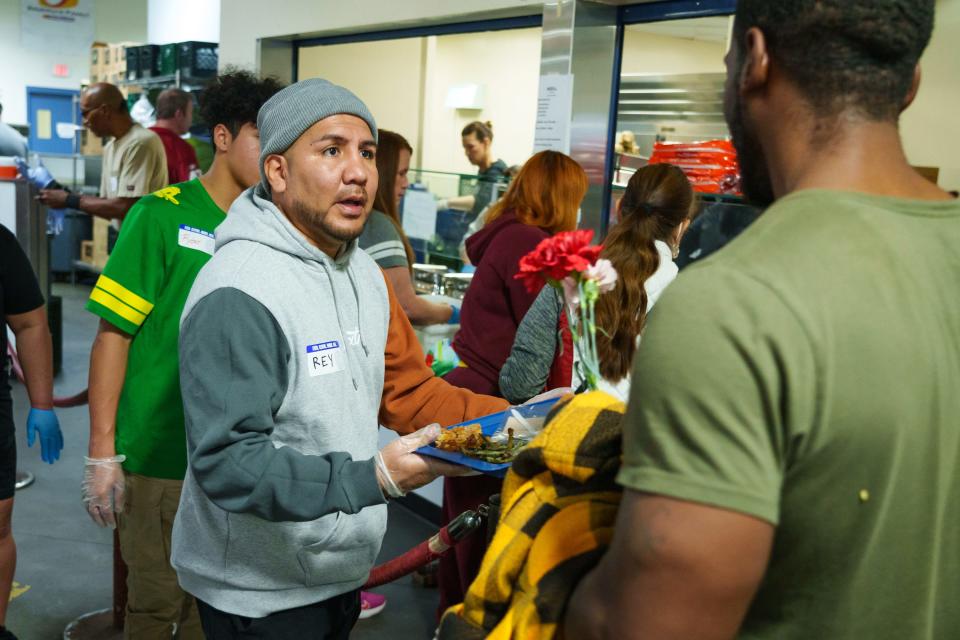 Ray Martinez Jr. hands trays of food to people at the Champions for the Homeless Thanksgiving event at the St. Vincent de Paul dining room on Nov. 24, 2022, in Phoenix.
