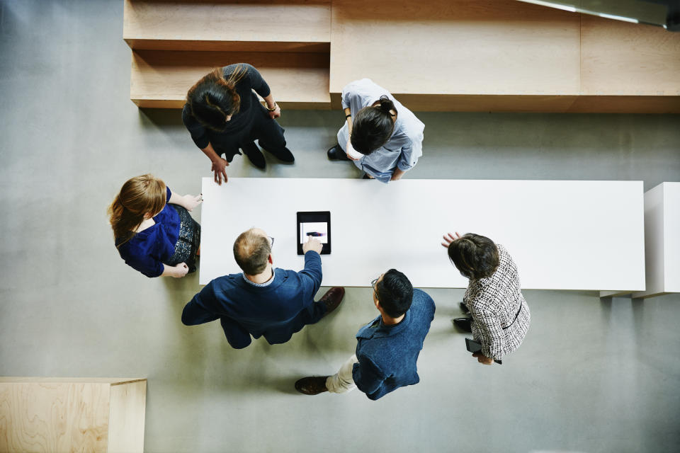 Overhead view of business colleagues discussing project on digital tablet