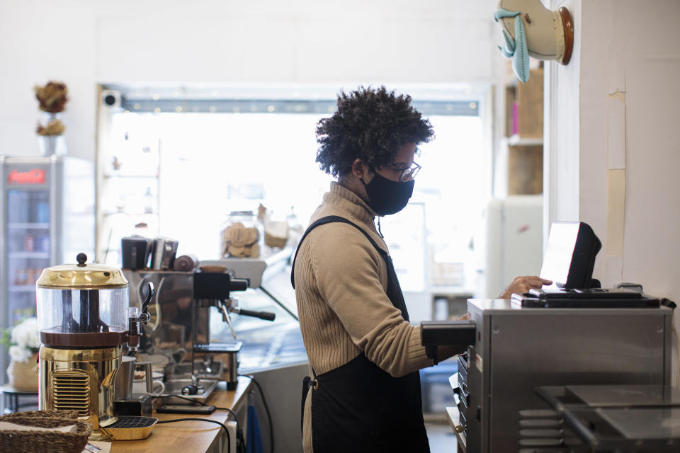 A worker in a cafe standing at a computer screen