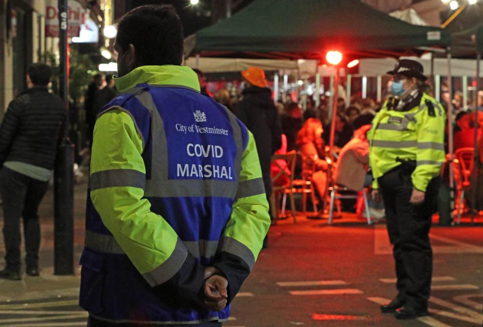 <p>A Covid Marshal and Police Officer at the junction between Frith Street and Old Compton Street in Soho, </p> (PA)