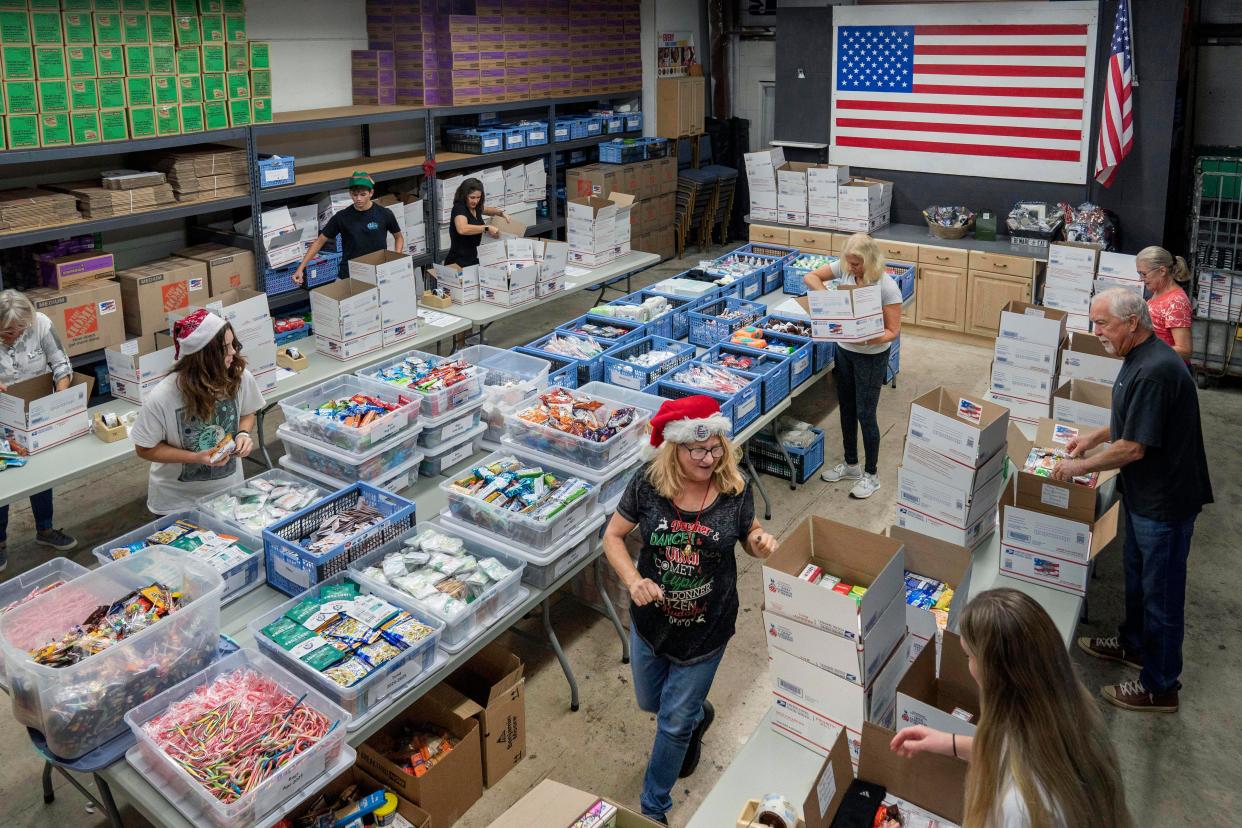 Volunteers led by Lynelle Chauncey Zelnar, center, pack boxes during the 20th annual Forgotten Soldiers Outreach holiday packing event in Lake Worth Beach, Florida on November 19, 2022. The care packages are being sent to members of the U.S. Armed Forces all over the world.
