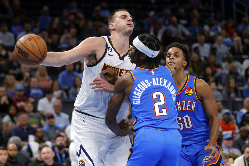 Denver Nuggets center Nikola Jokic, left, is defended by Oklahoma City Thunder guard Shai Gilgeous-Alexander, middle, and forward Jeremiah Robinson-Earl during the first half of an NBA basketball game Thursday, Nov. 3, 2022, in Oklahoma City. (AP Photo/Nate Billings)