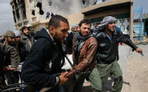 <p>Libyan rebel fighters carry out a comrade wounded during an effort to dislodge some ensconced government loyalist troops who were firing on them from a building (background) during house-to-house fighting on Tripoli Street in downtown Misrata April 20, 2011 in Misrata, Libya. (Photo by Chris Hondros/Getty Images) </p>