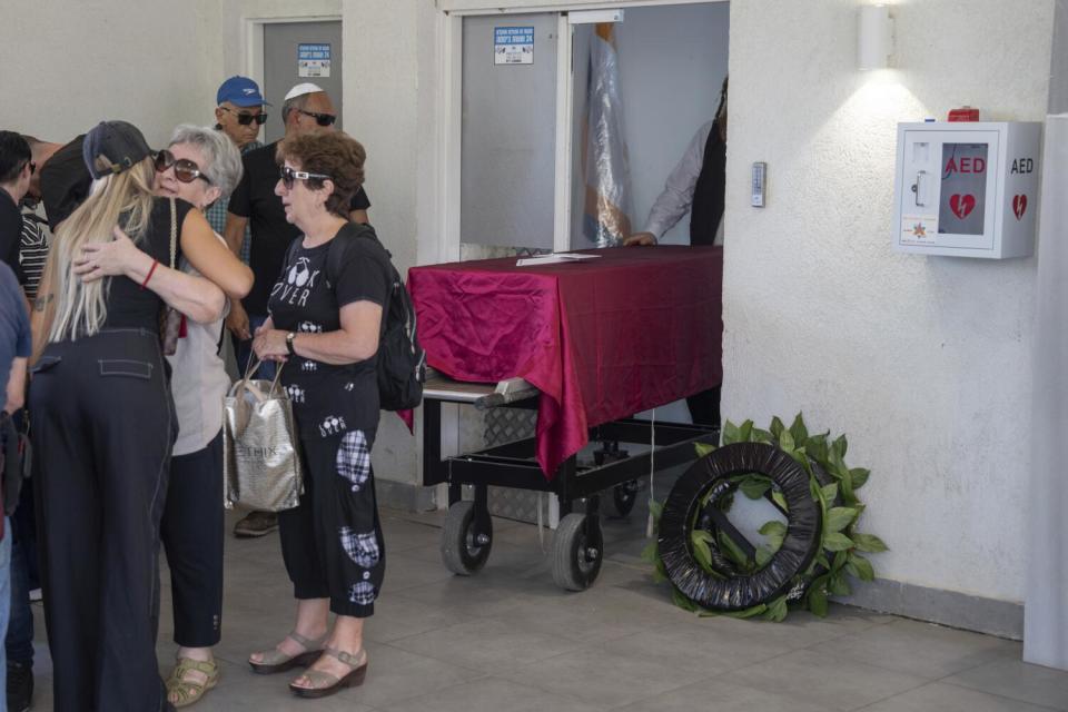 People comforting themselves near a coffin