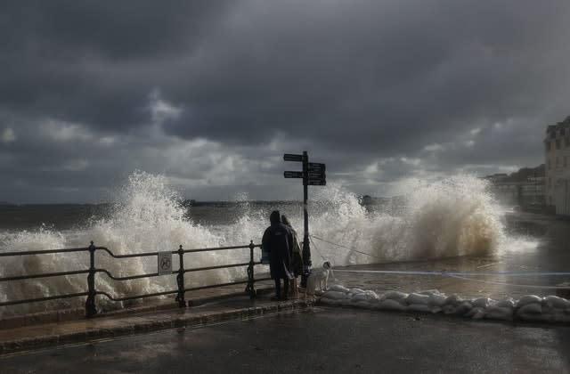 People watch the spectacle as waves crash along the coast at Swanage