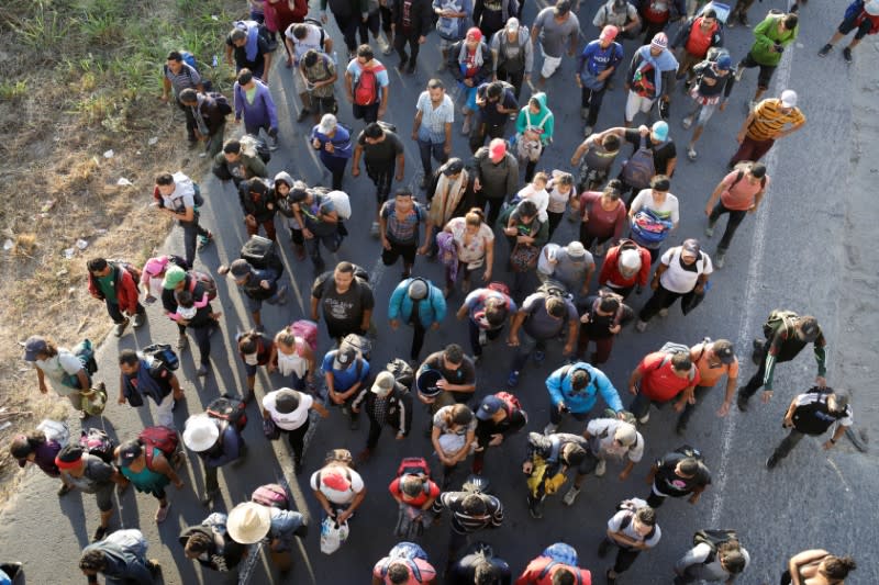 Migrants, mainly from Central America and marching in a caravan, walk on a road on the outskirts of Ciudad Hidalgo