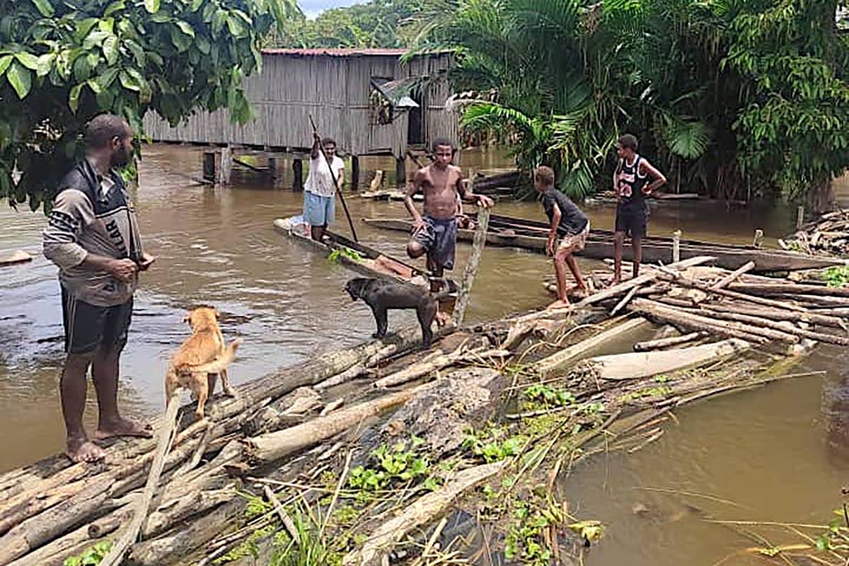 Locals on a makeshift bridge in the flooded Angriman Village in Angoram District (AFP)