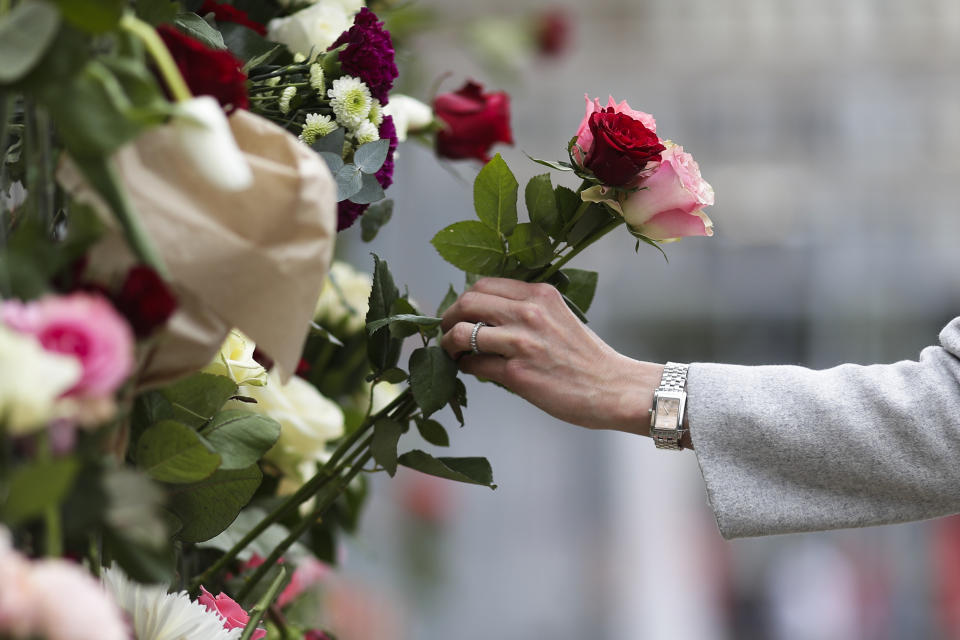 A woman places flowers on a fence following a suspected terror attack in central Stockholm, Sweden, Saturday, April 8, 2017. Swedish prosecutor Hans Ihrman said a person has been formally identified as a suspect "of terrorist offences by murder" after a hijacked truck was driven into a crowd of pedestrians and crashed into a department store on Friday. (AP Photo/Markus Schreiber)