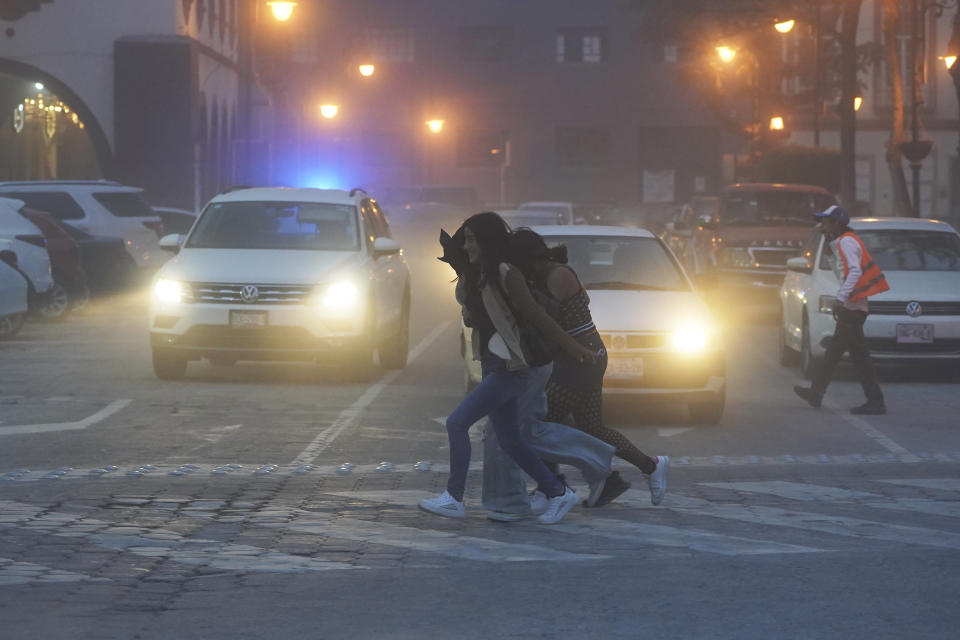 Women walk through the streets covered in ash from the Popocatépetl volcano in Atlixco, Mexico, Monday, May 22, 2023. The volcano's activity has increased over the past week. Evacuations have not been ordered, but authorities are preparing for that scenario and telling people to stay out of 7.5-mile (12-kilometer) radius around the peak. (AP Photo/Marco Ugarte)