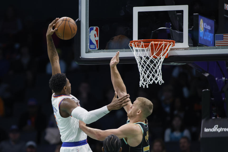 New York Knicks guard RJ Barrett, left, drives for a dunk against Charlotte Hornets center Mason Plumlee during the first half of an NBA basketball game in Charlotte, N.C., Friday, Dec. 9, 2022. (AP Photo/Nell Redmond)