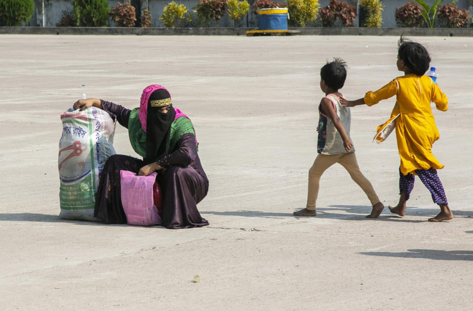 A Rohingya refugee rests as children walk past her as they wait to board a naval vessel that will take them to Bhasan Char island, in Chittagong, Bangladesh, Thursday, Nov. 25, 2012. Thousands have been relocated on the island in the Bay of Bengal from crammed camps near the Myanmar border. (AP Photo)