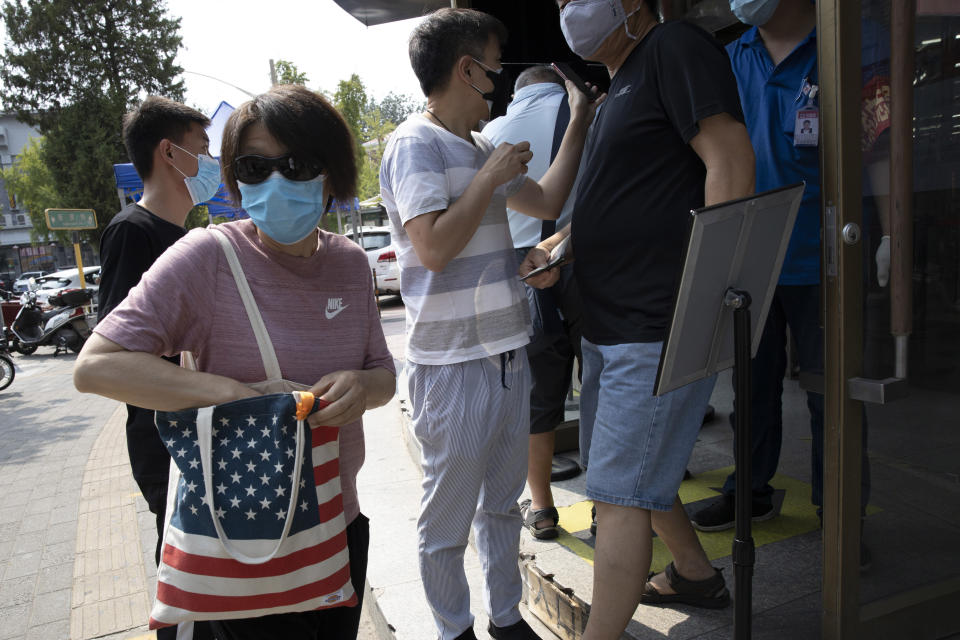 A resident wearing mask to curb the spread of the coronavirus carries a United States flag shopping bag in Beijing on Wednesday, July 8, 2020. China isn't seeking to confront or replace the United States as the world's top technological power, but will fight back against "malicious slander" and attacks from Washington, a foreign ministry spokesperson said Friday, responding to a litany of recent accusations from the Trump administration. (AP Photo/Ng Han Guan)