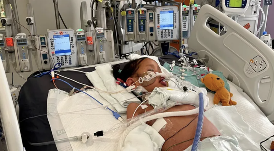 little girl in hospital bed hooked up to tubes, Taitlyn Ma, 7, spend weeks in the ICU after contracting an aggressive strep A infection (photo Taitlyns Journey/GoFundMe).
