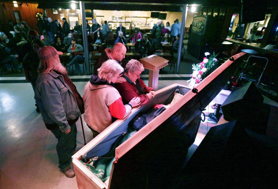 Family members pay their last respects to Jimmy Lehr at the All Around Bar in Taylor, Mich. on Thursday, Feb. 13, 2014. The suburban Detroit bar fulfilled the wish of their longtime employee who asked that his funeral be held at the watering hole where he worked for about 25 years. The 58-year-old died Feb. 7 after having pulmonary disease and congestive heart failure. A pine casket built at the bar was surrounded by flowers on the dance floor during a Wednesday wake. It's the same floor where Lehr's fourth wedding was held in 1996. (AP Photo/Carlos Osorio)