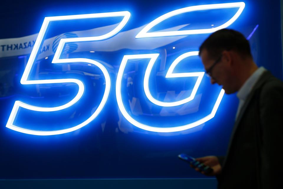 A man uses his phone next to a 5G hotspot sign at the Mobile World Congress (MWC) in Barcelona on February 26, 2019. - Phone makers will focus on foldable screens and the introduction of blazing fast 5G wireless networks at the world's biggest mobile fair as they try to reverse a decline in sales of smartphones. (Photo by Pau Barrena / AFP)        (Photo credit should read PAU BARRENA/AFP/Getty Images)