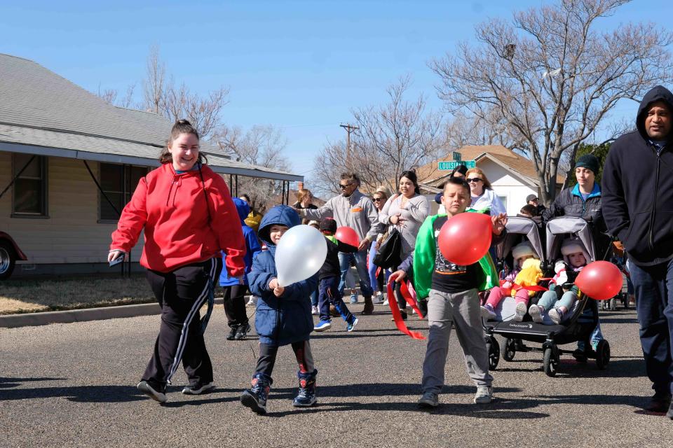 Familes walk down 7th Street Saturday at Storybridge's “Cat in the Hat March” celebrating Read Across America in Amarillo.