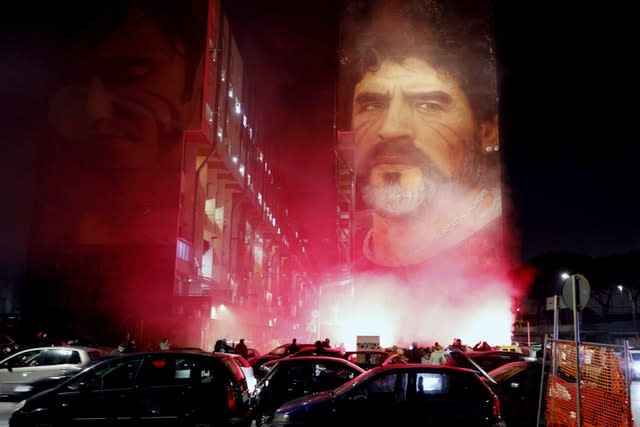 Fans light flares as they gather under a mural depicting Diego Maradona in Naples 