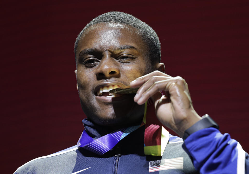 FILE - In this Sept. 29, 2019, file photo, gold medal winner Christian Coleman of the United States, bites on his medal during ceremonies for the men's 100m at the World Athletics Championships in Doha, Qatar. Men's 100-meter world champion Christian Coleman was banned for two years on Tuesday, Oct. 27, 2020, for missing three doping control tests. Track and field's Athletics Integrity Unit said Coleman will be banned until May 2022, forcing him to miss the Tokyo Olympics next year. (AP Photo/Nariman El-Mofty, File)