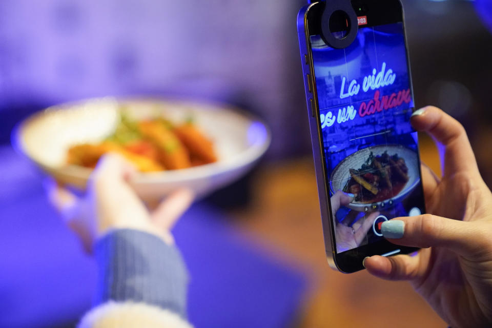 Content creator Jensen Savannah produces a client video at El Puro Cuban Restaurant, Thursday, March 14, 2024, in Charlotte, N.C. (AP Photo/Erik Verduzco)