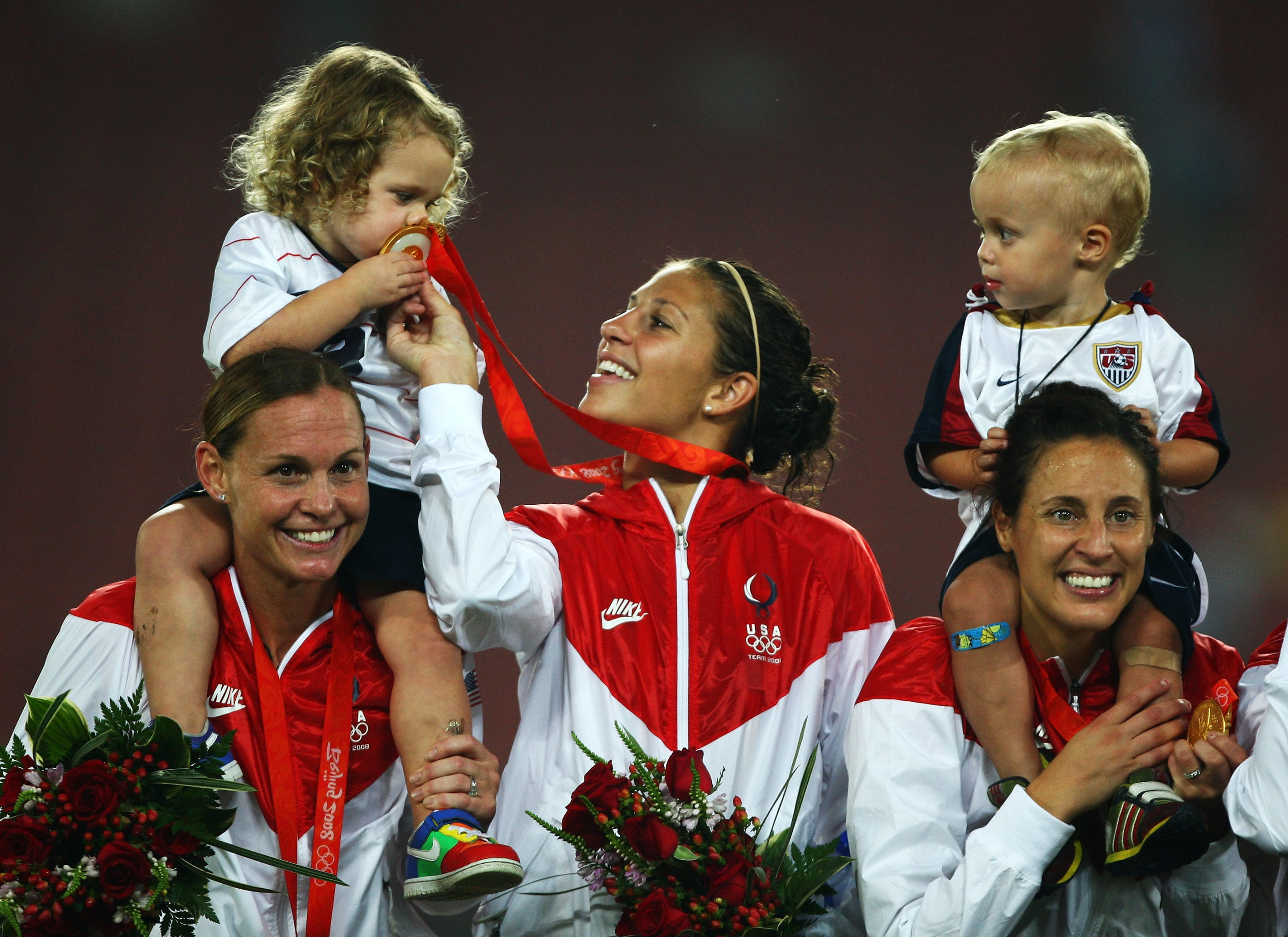 BEIJING - AUGUST 21:  (L-R)USA team members Christie Rampone, Carli Lloyd, Kate Markgraf and children pose on the podium with their Gold medals after the Women's Football on Day 13 of the Beijing 2008 Olympic Games on August 21, 2008 at Worker's Stadium in Beijing, China.  (Photo by Mike Hewitt/Getty Images)