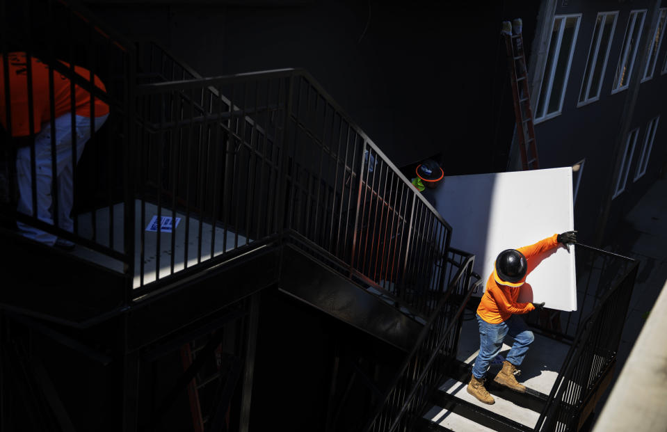 FILE - In this June 28, 2019, file photo construction workers carry material down a staircase while working on a new mixed-use development featuring apartments and retail space along the BeltLine, a former railroad corridor converted into parks and trails, in Atlanta. The shareholder comes first has for years been the mantra of the Business Roundtable, a group representing the most powerful CEOs in America. The group on Monday, Aug. 19, released a new mission statement that implies a foundational shift; a step back from shareholder primacy. (AP Photo/David Goldman, File)