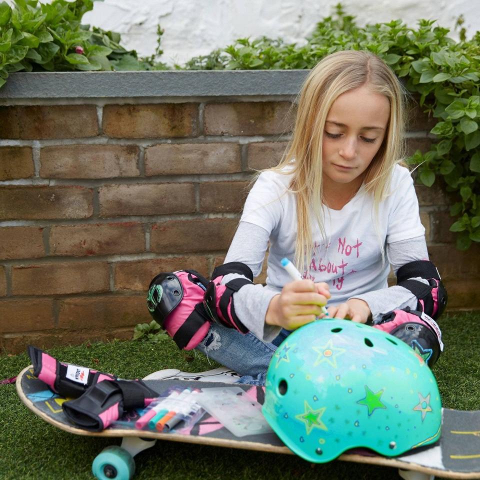 A girl coloring on a teal helmet