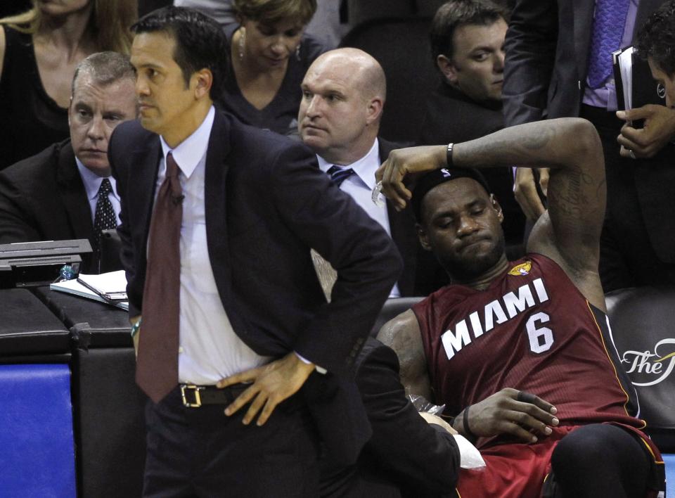 Miami Heat's LeBron James sits on the bench after hurting his leg as coach Erik Spoelstra watches the game during the fourth quarter against the San Antonio Spurs in Game 1 of their NBA Finals basketball series in San Antonio