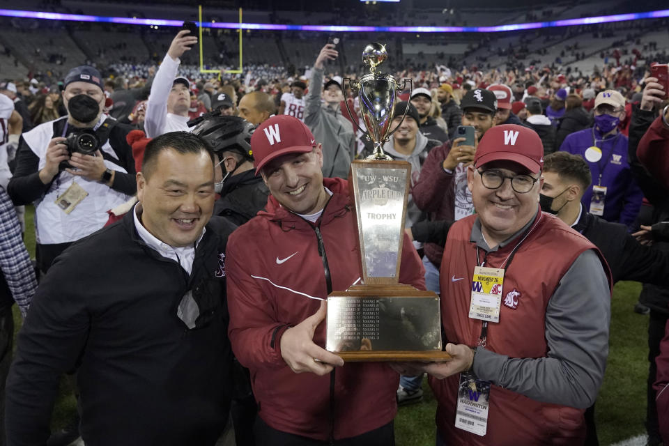 Washington State coach Jake Dickert, center, holds the Apple Cup Trophy between athletic director Pat Chun, left, and WSU President Kirk Schultz after the team's 40-13 win over Washington in an NCAA college football game, Friday, Nov. 26, 2021, in Seattle. (AP Photo/Ted S. Warren)