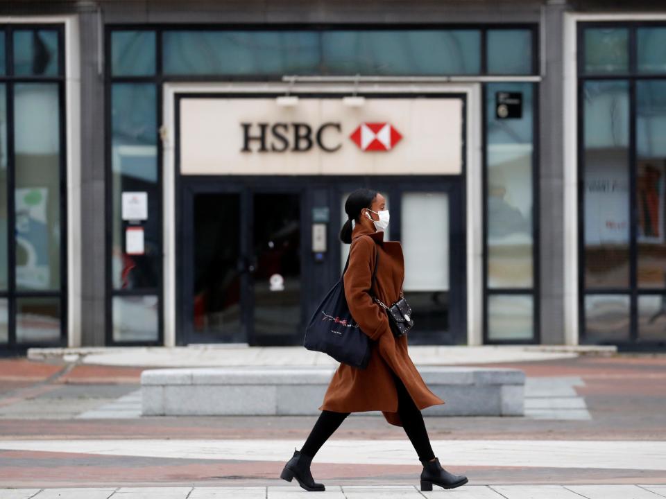 FILE PHOTO: A woman wearing a protective face mask walks past a logo of HSBC bank at the financial and business district of La Defense near Paris as France begun a gradual end to a nationwide lockdown due to the coronavirus disease (COVID-19), May 11, 2020. REUTERS/Gonzalo Fuentes