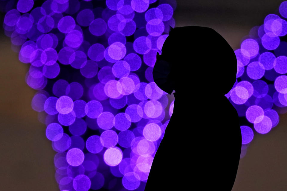 A woman wears masks to prevent the spread of the coronavirus as she looks at a holiday display on a mild day Saturday, Dec. 26, 2020, in a park in Lenexa, Kan. (AP Photo/Charlie Riedel)