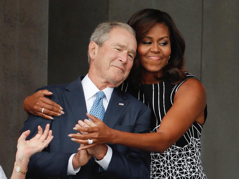 First lady Michelle Obama hugs former President George W. Bush during the dedication ceremony for the Smithsonian Museum of African American History and Culture on the National Mall in Washington, Saturday, Sept. 24, 2016.