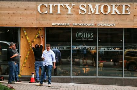 Workers repair a broken window at the City Smoke restaurant on Trade Street after protests against the police shooting of Keith Scott, in Charlotte, North Carolina, U.S. September 22, 2016. REUTERS/Jason Miczek