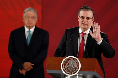 Mexico's Foreign Minister Marcelo Ebrard holds a document as Mexico's President Andres Manuel Lopez Obrador looks on during a news conference at National Palace in Mexico City