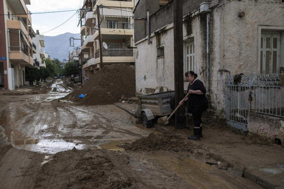 A woman shovels mud outside her house in the storm-hit city of Volos, Greece, where power and water outages remained in some districts, on Friday, Sept. 29, 2023. Bad weather has eased in central Greece leaving widespread flooding and infrastructure damage across the farming region that has been battered by two powerful storms in less than a month. (AP Photo/Petros Giannakouris)