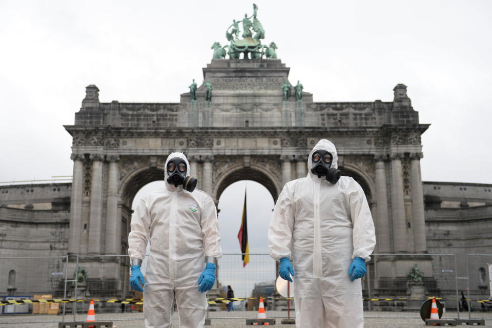 Belgian military personnel members wearing full protective suits stand in front of the Cinquantenaire arch during the disinfection of an ambulance amid the coronavirus disease (COVID-19) outbreak in Brussels, Belgium November 13, 2020. REUTERS/Johanna Geron