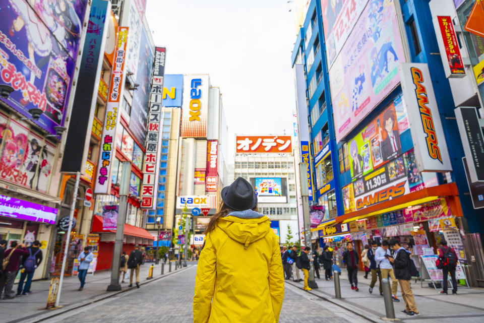 Woman with yellow jacket walking in the electronic town district of Tokyo, Japan