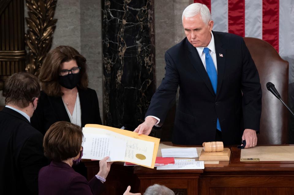 Vice President Mike Pence hands the electoral certificate from the state of Arizona to Sen. Amy Klobuchar, D-Minn., as he presides over a joint session of Congress as it convenes to count the Electoral College votes cast in November's election, at the Capitol in Washington, Wednesday, Jan. 6, 2021. (Saul Loeb/Pool via AP)