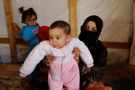 Syrian refugee Asheqa holds her unregistered baby daughter Nour inside a tent at a refugee camp near the town of Baalbek in LebanonÕs Bekaa valley, March 3, 2016. REUTERS/Mohamed Azakir